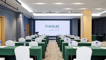 A conference room with rows of tables, chairs, and a presentation screen displaying 'Fairfield by Marriott Harbin Downtown'.