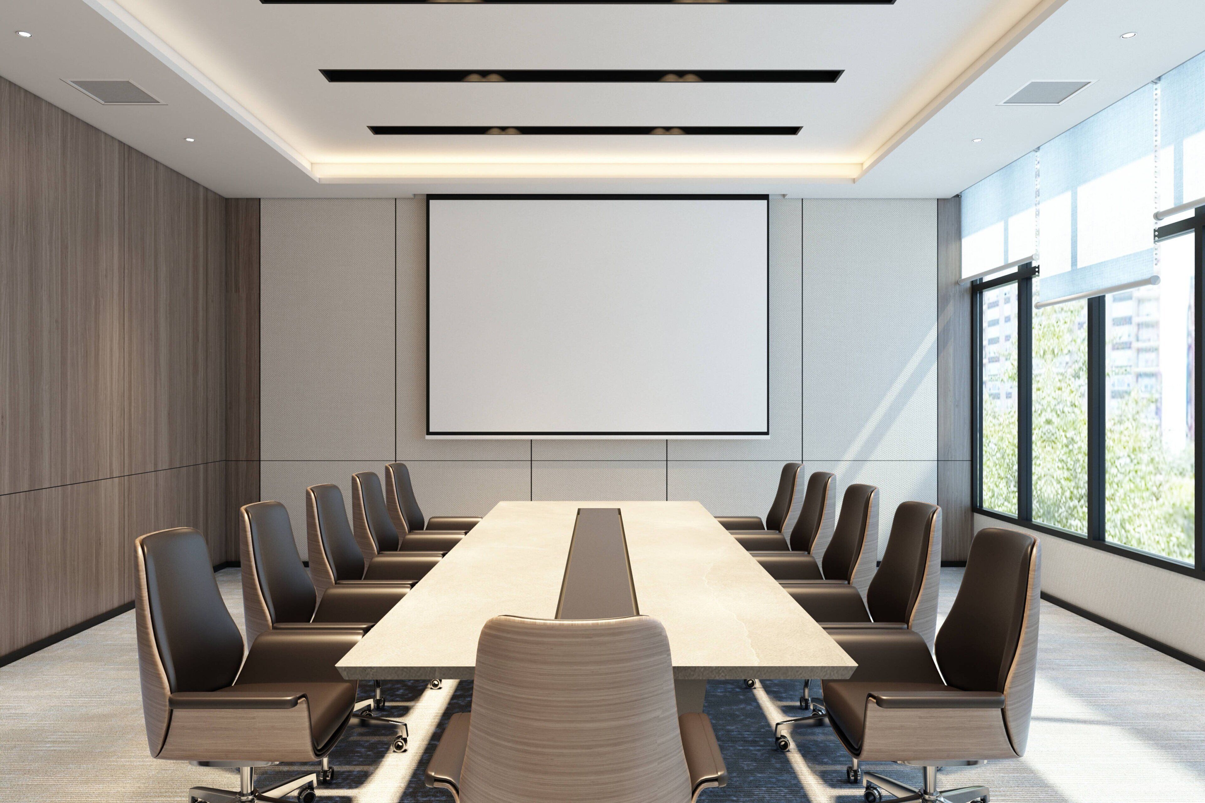 A conference room with a long table and modern chairs, a large screen, and large windows.