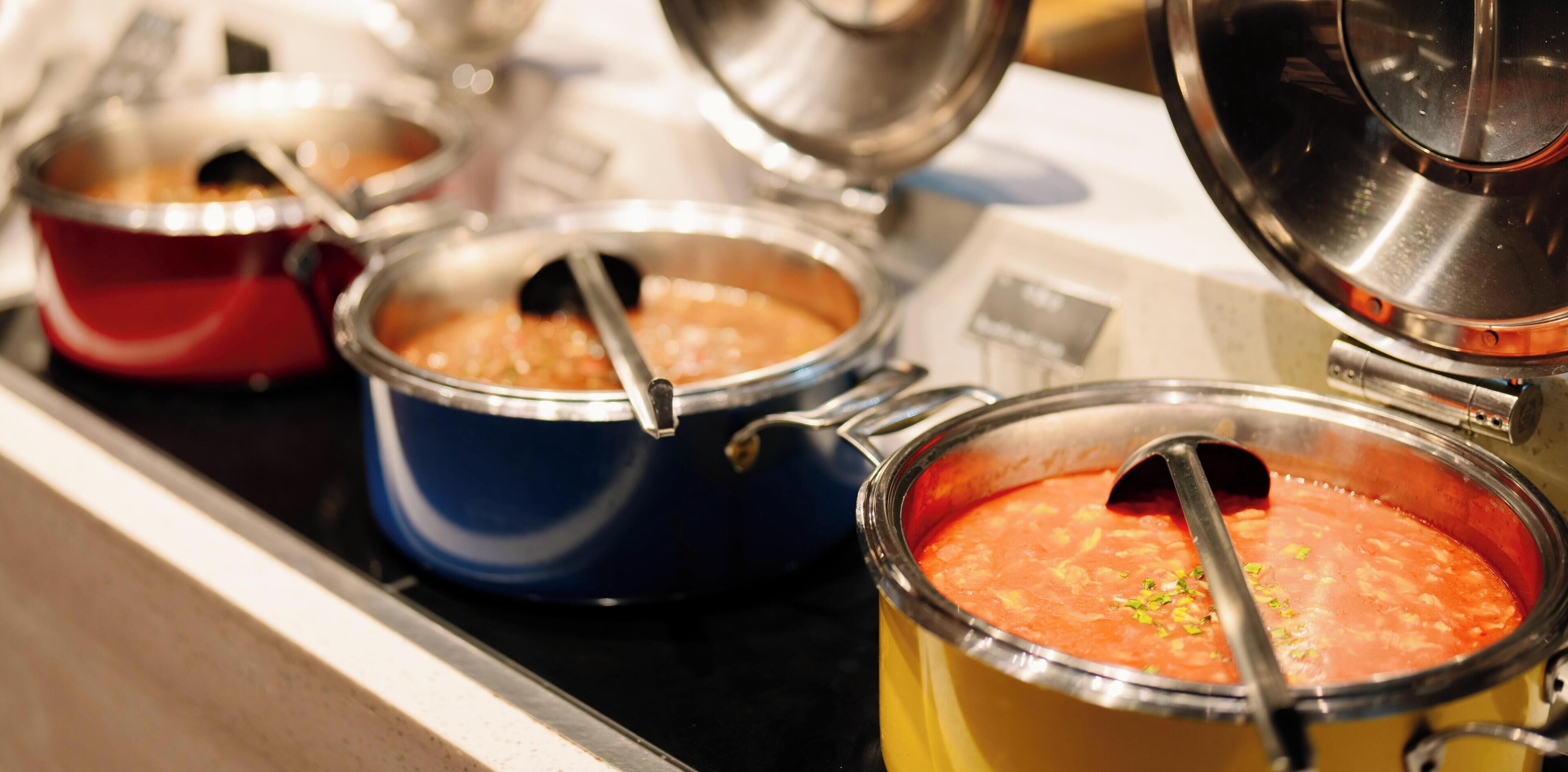 Uma cozinha com várias panelas em um fogão, provavelmente contendo sopa ou ensopado.