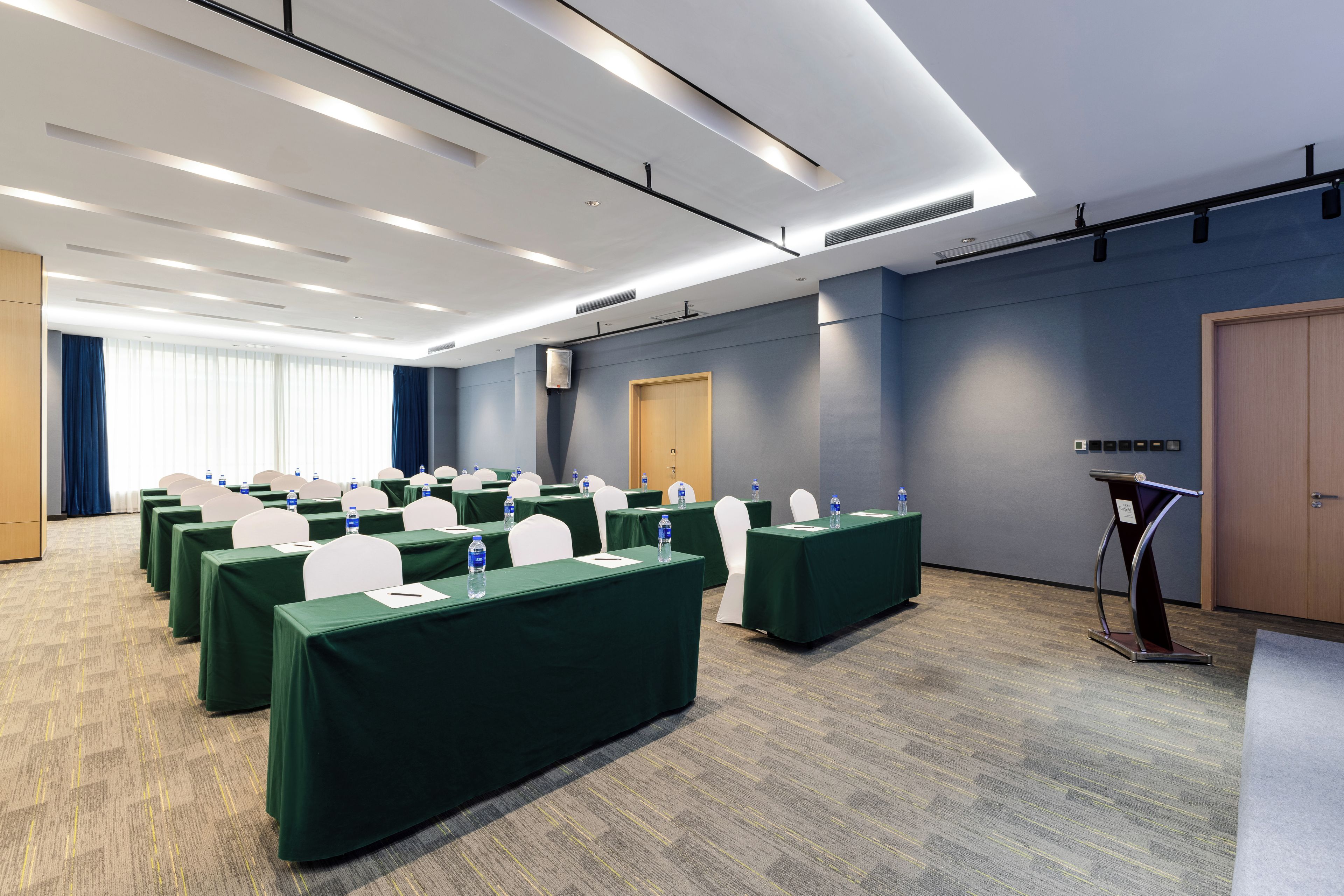 Un salón de conferencias con mesas, sillas y un atril.
