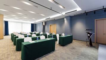 Un salón de conferencias con mesas, sillas y un atril.