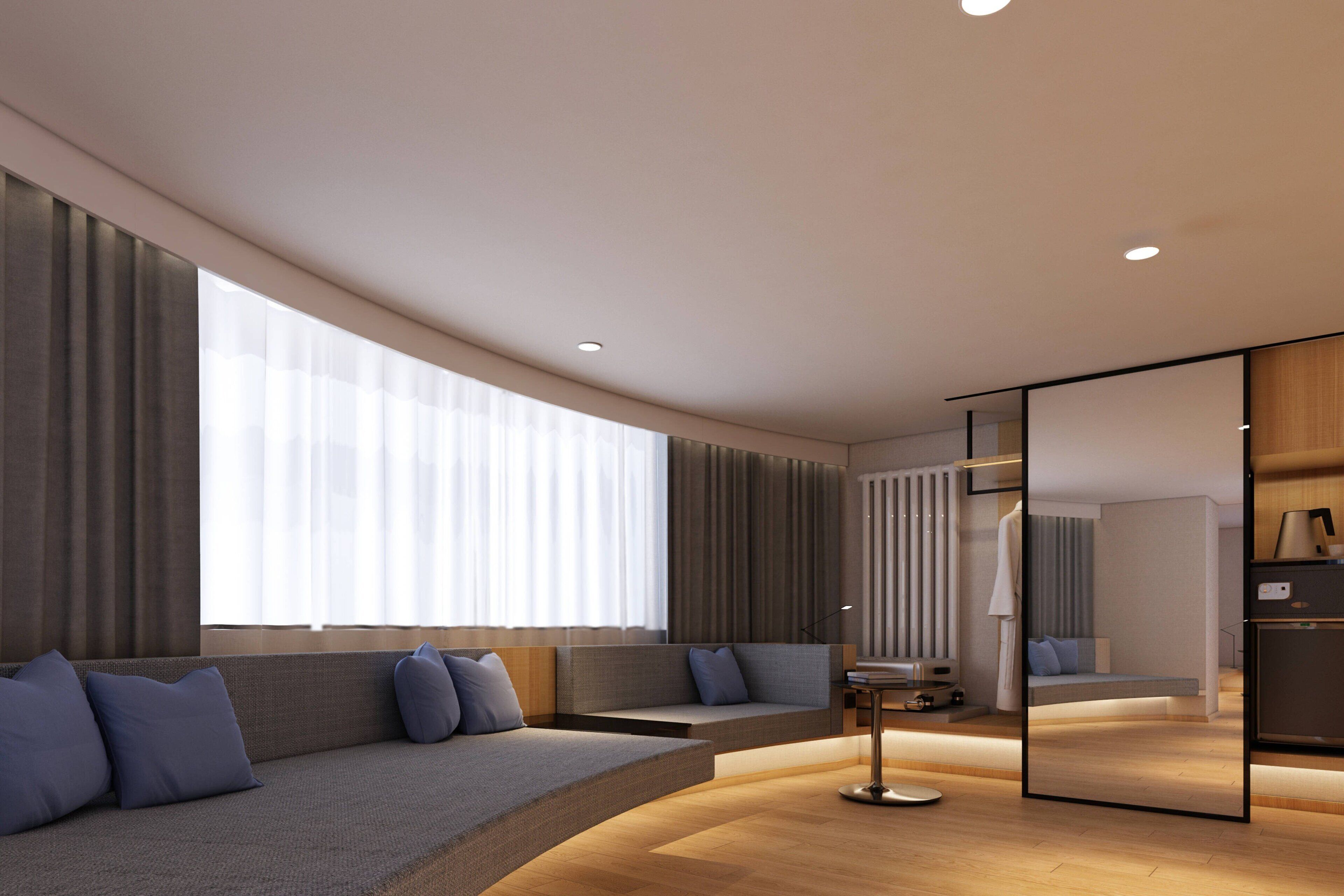 Une chambre d’hôtel moderne avec un canapé incurvé, un grand miroir et un plancher en bois.