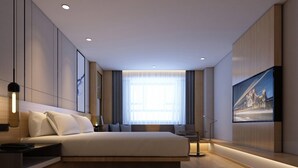 Una habitación de hotel moderna con una cama grande, un televisor de pantalla plana montado en la pared y un amplio ventanal con cortinas.