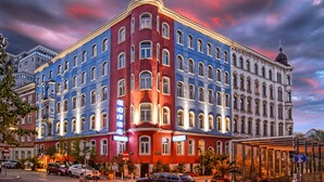 Hotel com vários andares e estilo arquitetônico clássico, com entrada de destaque no canto e várias janelas.