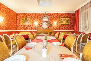 Comedor con una larga mesa dispuesta para una comida, rodeada de sillas con tapicería floral.