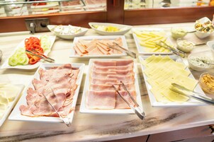 Um buffet com diversos alimentos, incluindo carnes fatiadas, queijos e vegetais.