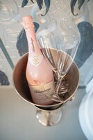 Uma garrafa de champanhe rosé Schlumberger num balde de metal, com dois flûtes de champanhe vazios.
