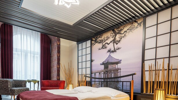 Quarto moderno com uma cama grande, vista para o mar através de janelas do chão ao teto e um mural de parede em estilo tradicional japonês.
