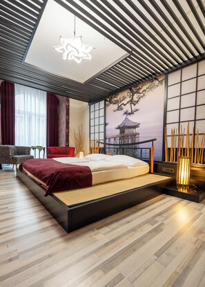 A modern bedroom with a large bed, a view of the sea through floor-to-ceiling windows, and a traditional Japanese-style wall mural.