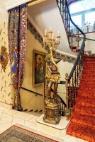 Uma escadaria imponente com grades ricamente decoradas, um candelabro e uma estátua.