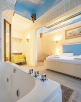 Un'elegante camera da letto con un ampio letto, una zona salotto separata e una vasca da bagno.