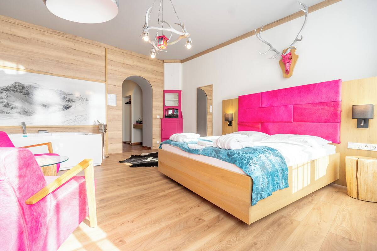 A modern bedroom with a wooden bed, a pink headboard, and a large window.