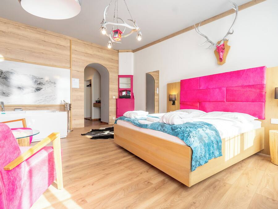 A modern bedroom with a wooden bed, a pink headboard, and a large window.