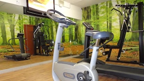 Una bicicleta estática en un gimnasio con un mural de un bosque en la pared.