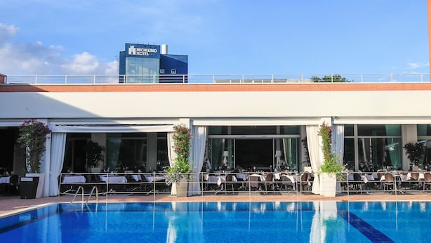 Hotel Michelino con zona de piscina que ofrece asientos exteriores y vista del edificio del hotel.