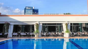 Una piscina al aire libre de temporada, sombrillas