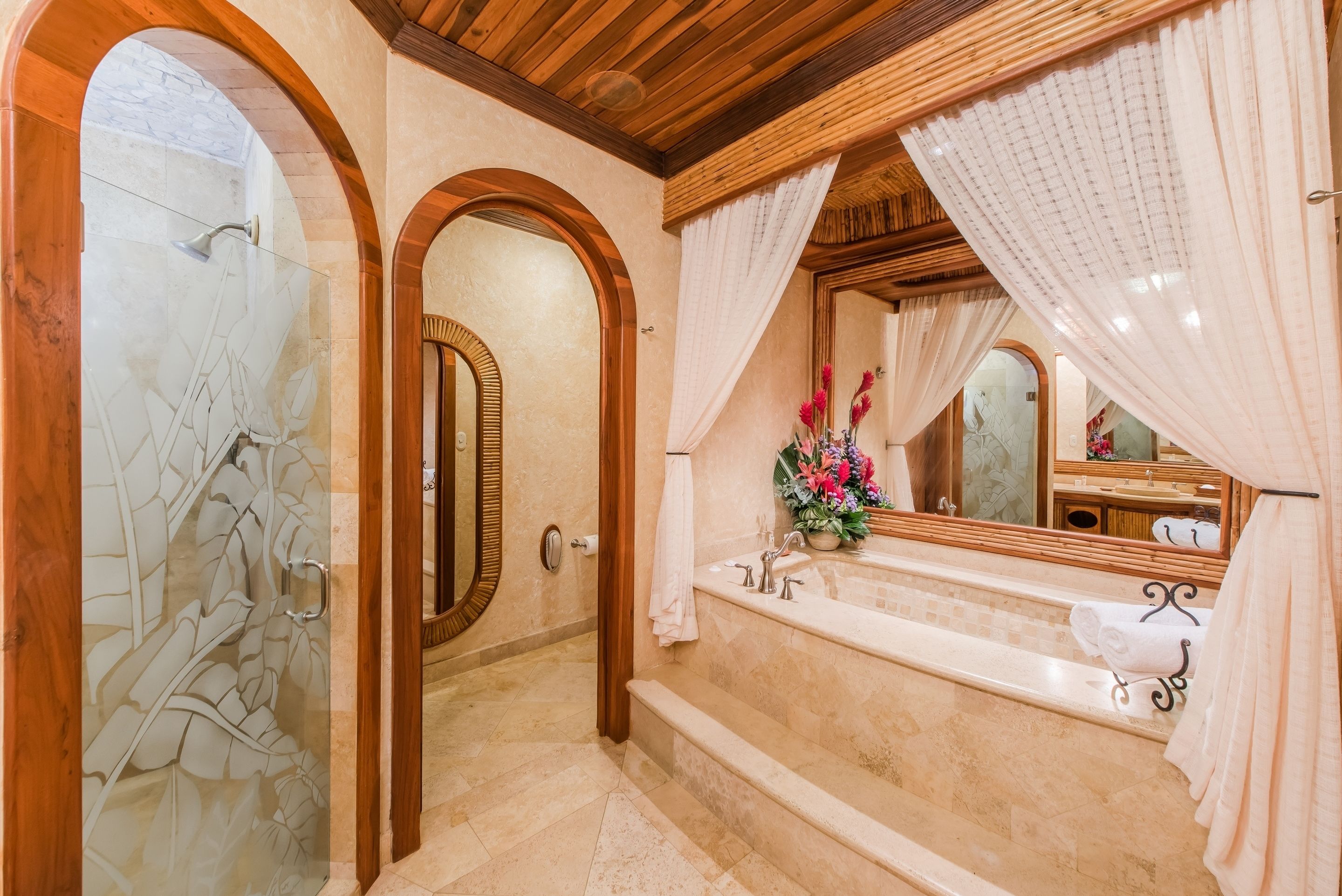 A bathroom with a large mirror, a bathtub, and a shower area.