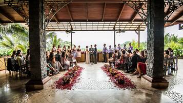 An outdoor wedding ceremony with guests seated on either side of a central aisle.