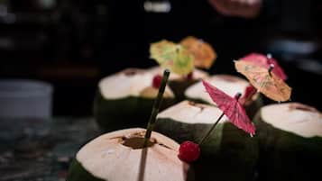 A bar counter with several coconut drinks garnished with umbrellas and cherries.