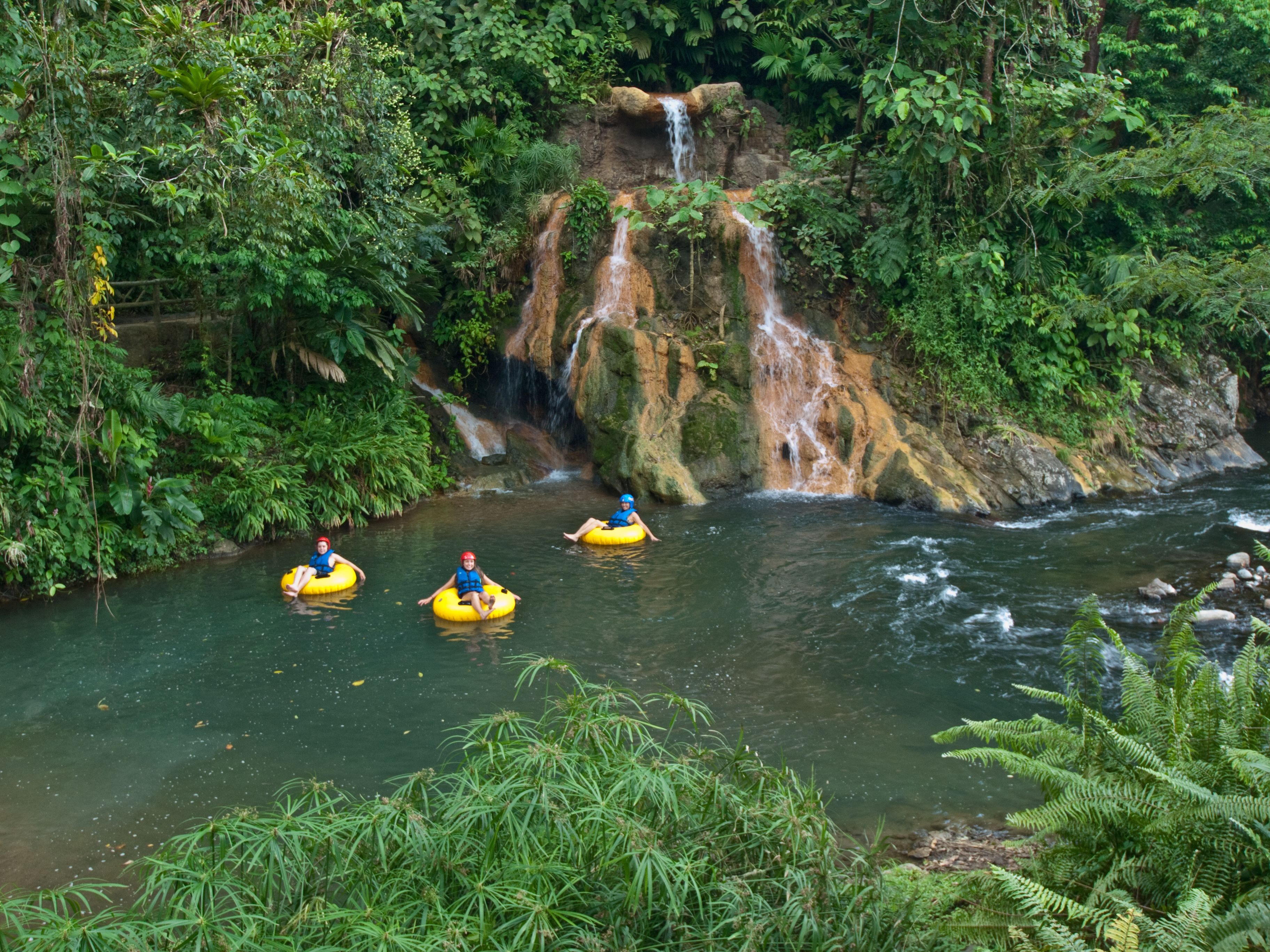 Um rio com uma cascata e três pessoas em botes amarelos.
