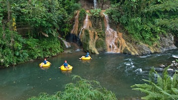 Um rio com uma cascata e três pessoas em botes amarelos.