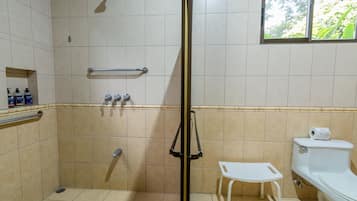 Un baño con ducha, inodoro y una pequeña ventana.