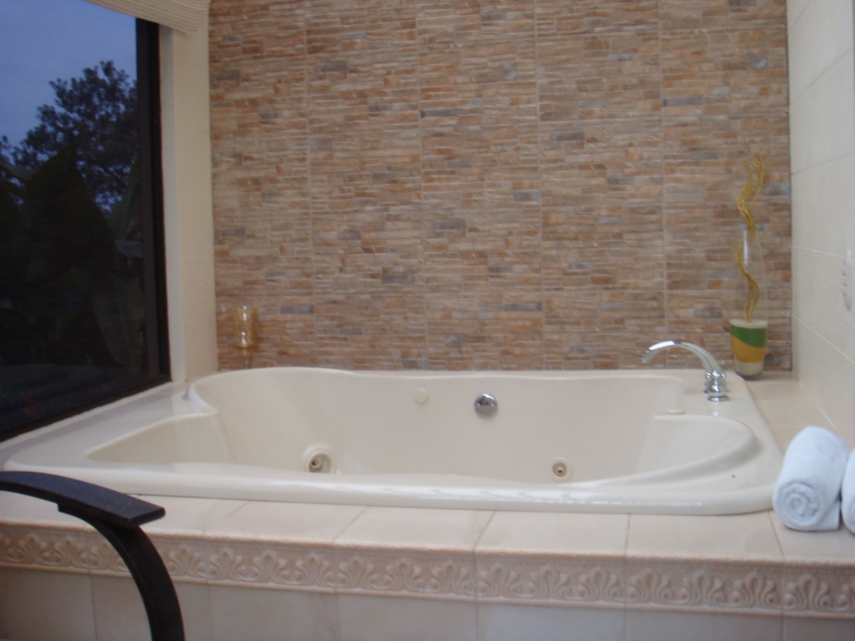Un baño con una bañera grande, una ventana y un detalle decorativo en la pared.