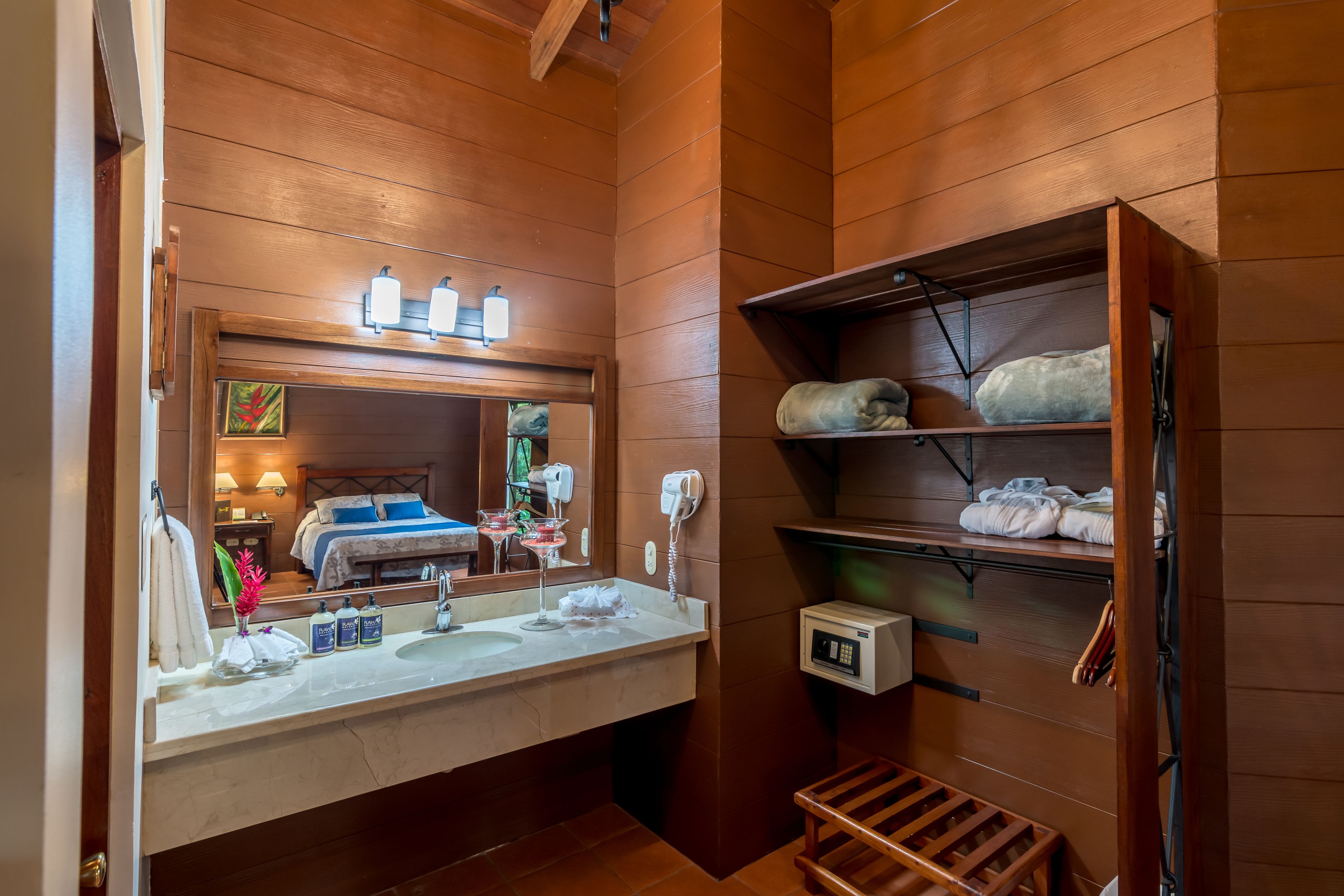 Une salle de bain avec un intérieur en bois, un grand miroir, un lavabo double et une étagère avec des serviettes.