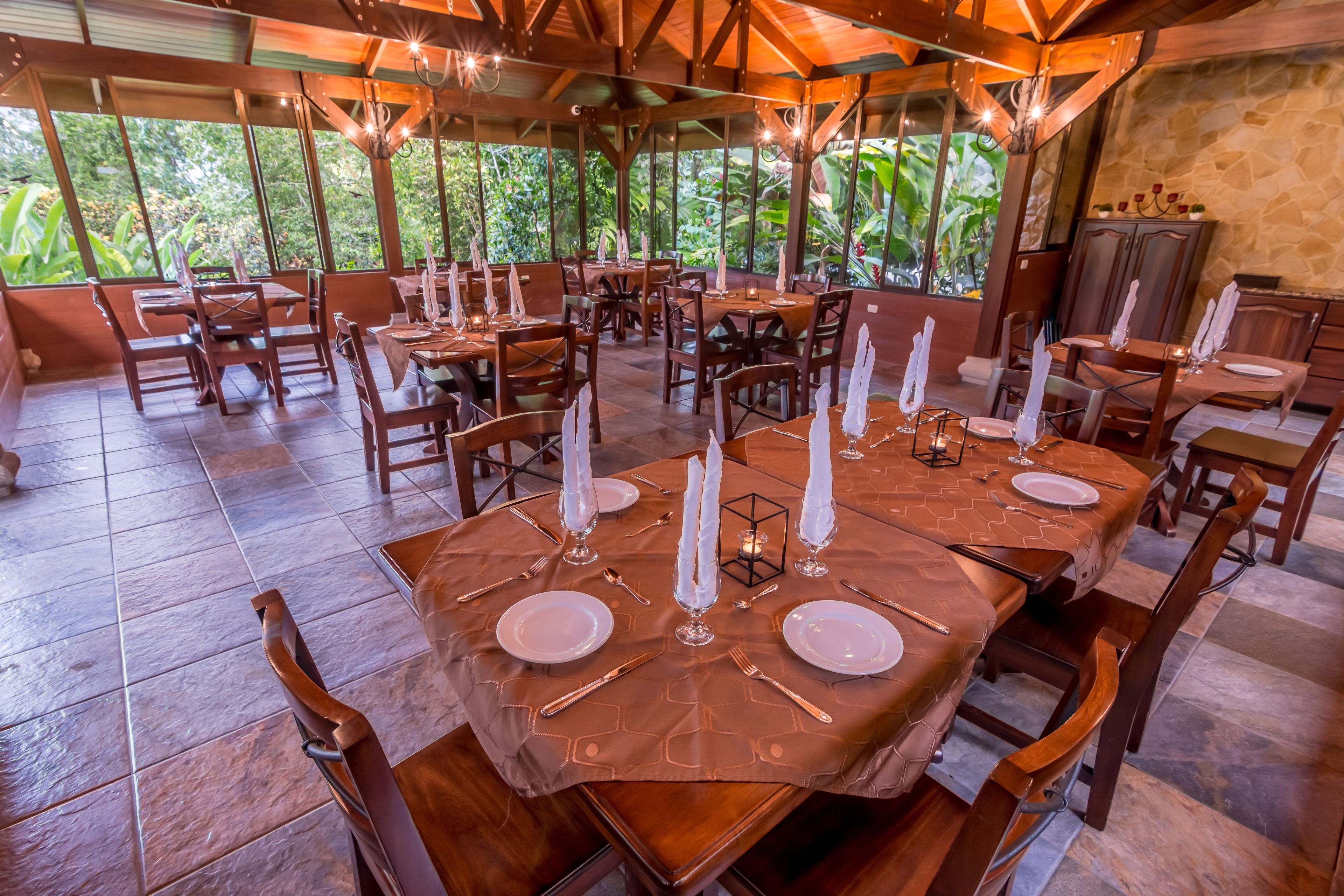 A restaurant with multiple tables set for dining, featuring hexagonal tablecloths and candle centerpieces.