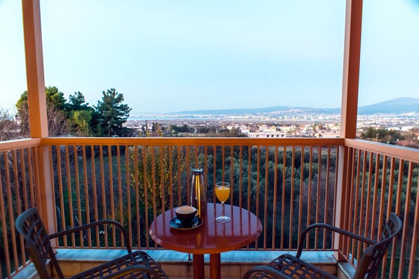 A balcony with a table, two chairs, a coffee cup, and a glass of orange juice.