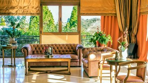 Un salon spacieux avec une grande fenêtre, un canapé en cuir marron, une table basse en bois et une chaise en bois.