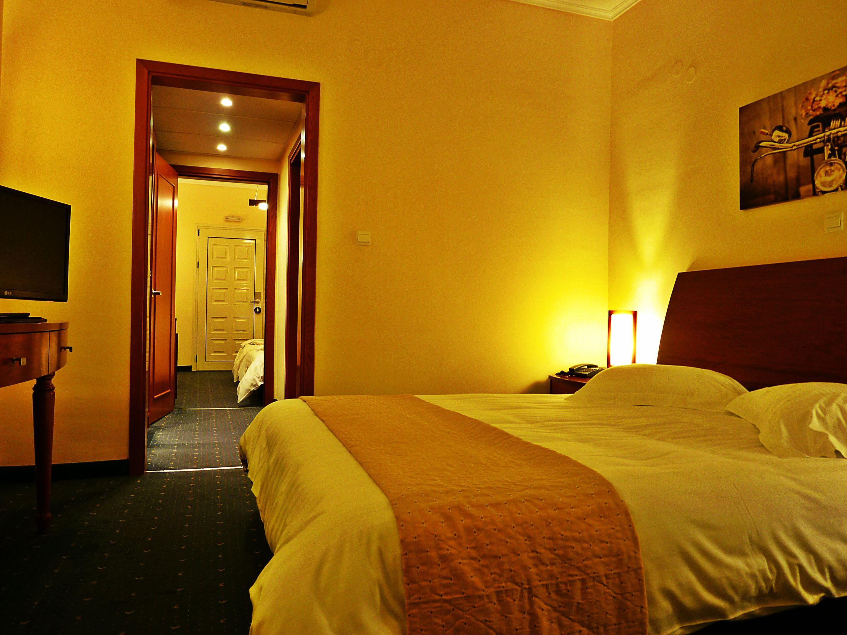 A hotel room with a bed, a television, and a door leading to another room.