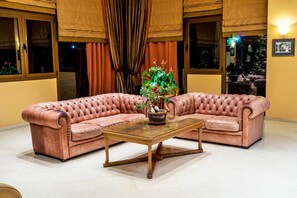 Una sala de estar con dos sofás de cuero marrón, una mesa de centro de vidrio y una planta en maceta.