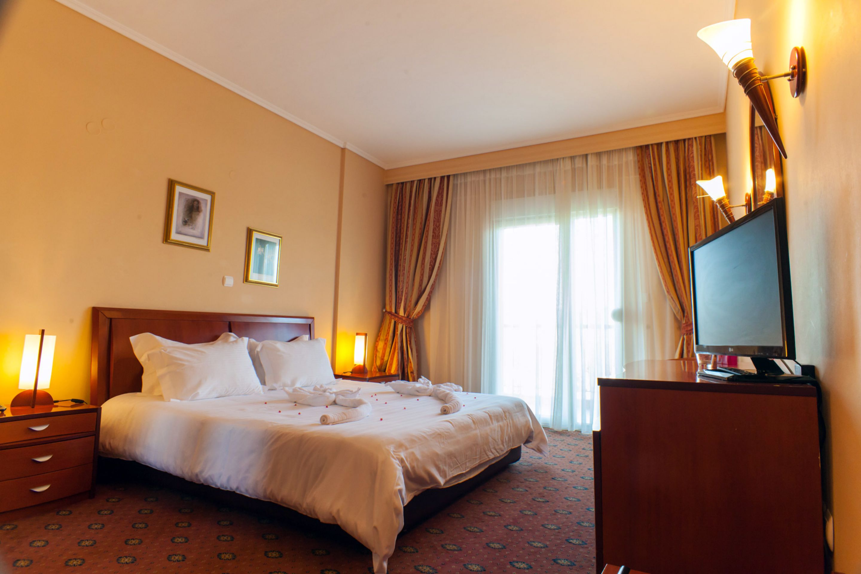 Una habitación de hotel con una cama grande, televisión y escritorio.