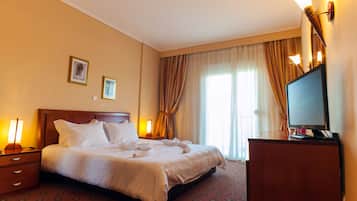 Una habitación de hotel con una cama grande, televisión y escritorio.