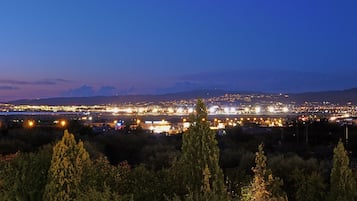 A nighttime cityscape with a view of a city and distant mountains.