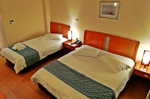 Habitación de hotel con dos camas, cabeceros de madera, mesitas de noche con lámparas y un cuadro enmarcado en la pared.