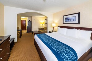 A hotel room with a large bed, a desk, a chair, a lamp, and a framed picture on the wall. - Comfort Inn & Suites Edson - Yellowhead Highway (Edson)