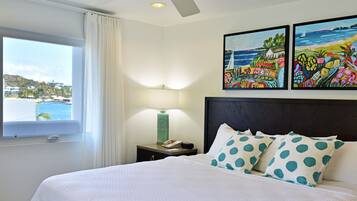 A hotel room with a bed, a nightstand, a lamp, and two paintings on the wall.