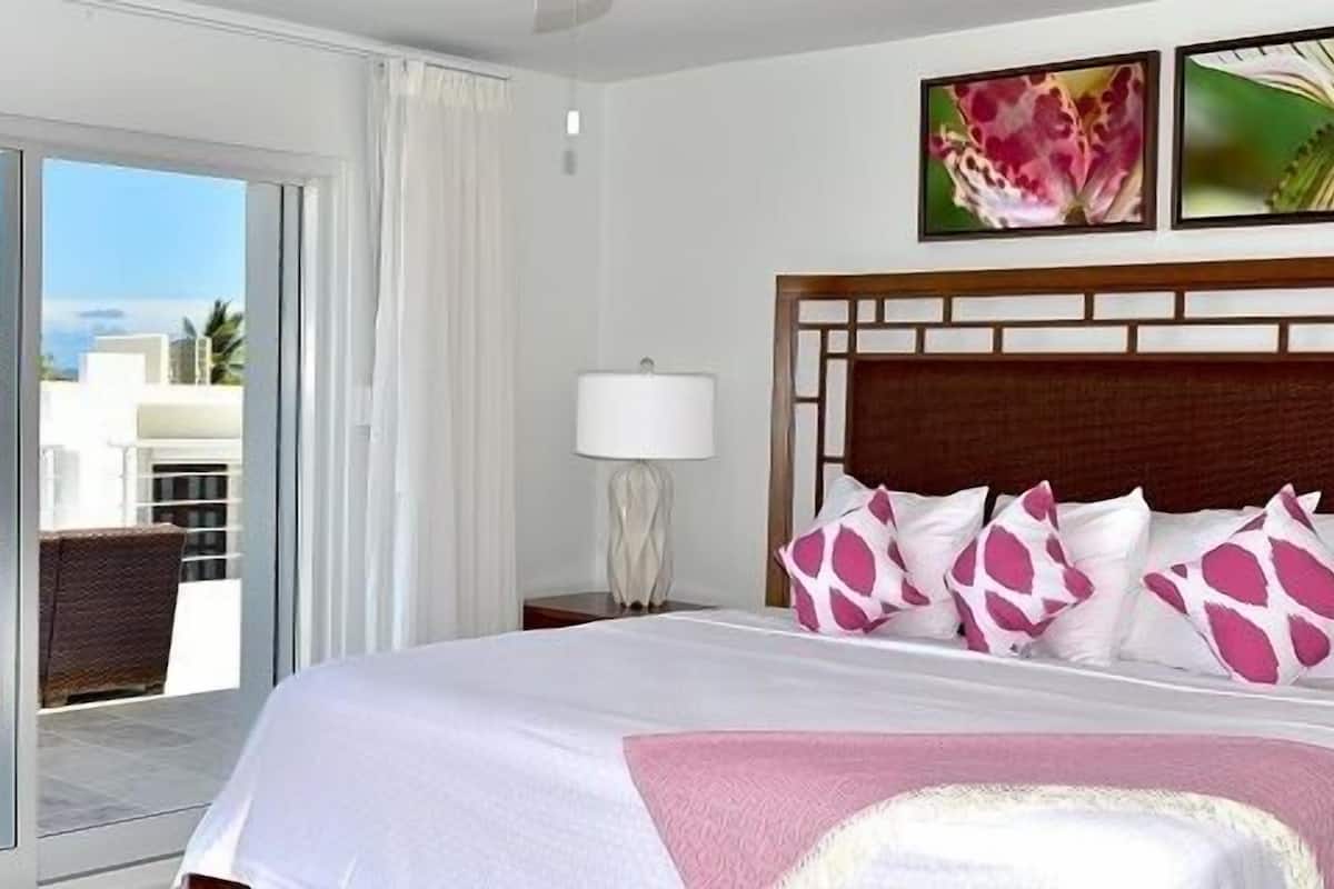 Ein Hotelzimmer mit einem großen Bett, Meerblick und einem Balkon mit Gartenmöbeln.
