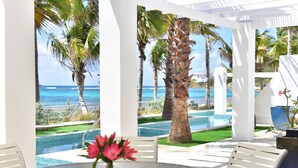 Un patio con piscina, palmeras y vista al océano.