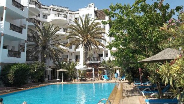 A hotel with a swimming pool, palm trees, and a clear blue sky. - Flathotel (Agadir)