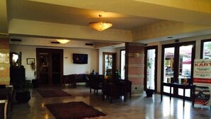 A spacious lobby with a high ceiling, a television mounted on the wall, and a reception desk. - Flathotel (Agadir)