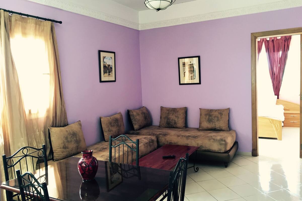 A living room with a sofa, a dining table with chairs, and a vase.