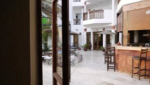 A spacious outdoor area with a bar and seating, surrounded by white buildings with balconies. - Flathotel (Agadir)