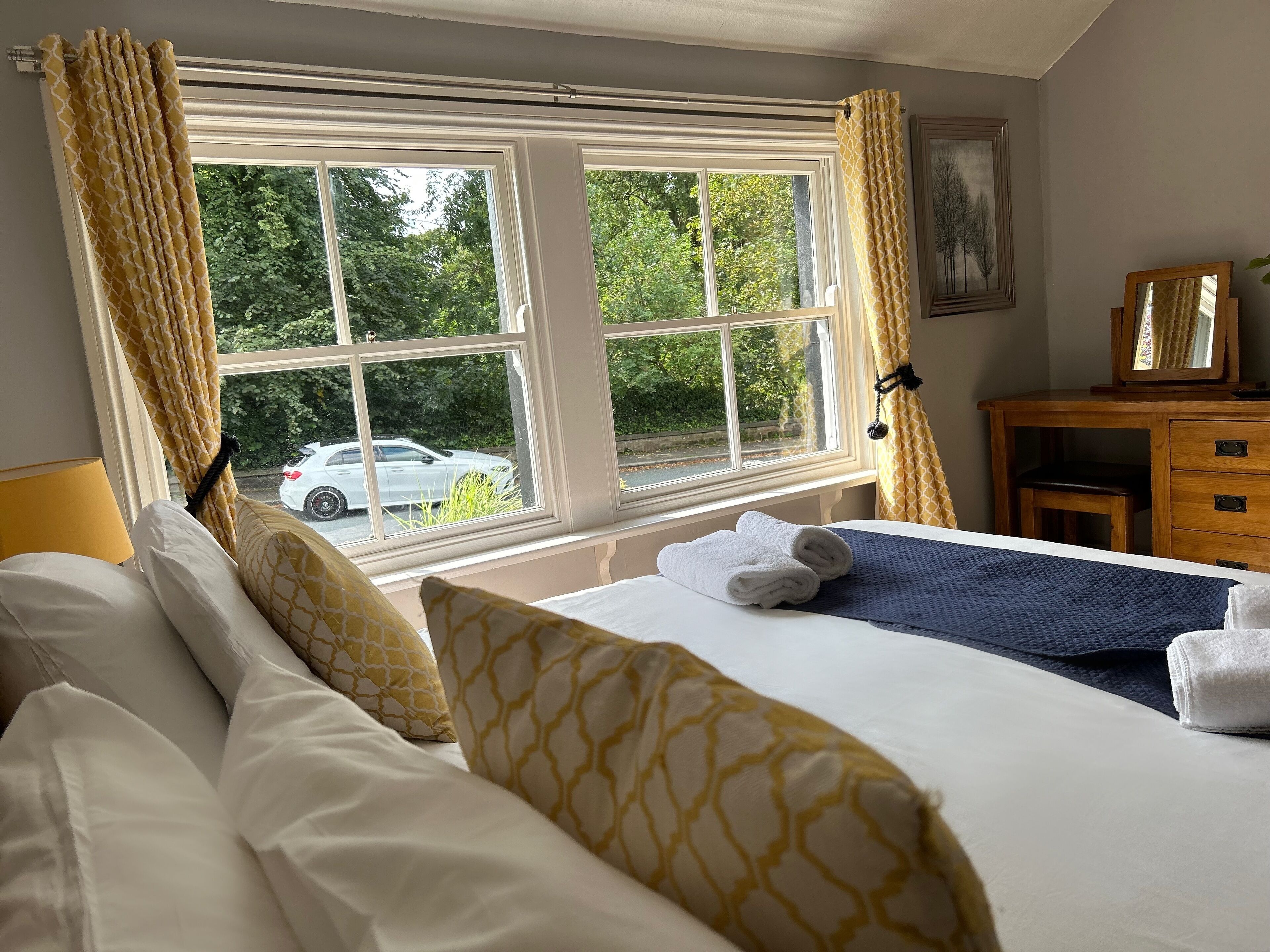 A hotel room with a bed, a desk, and a window with curtains.