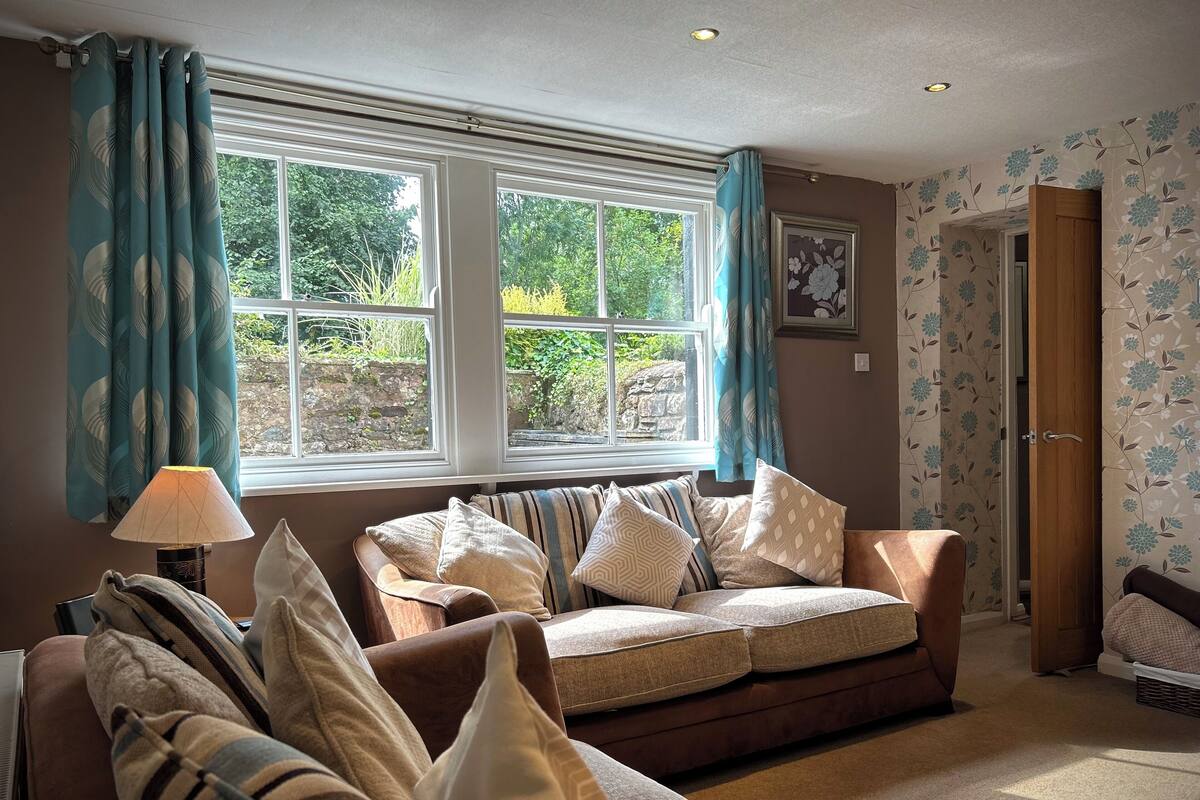 A cozy living room with a brown sofa, striped cushions, and a lamp.