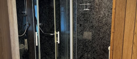 Een moderne badkamer met een douchecabine van glas, een toilet en een houten vloer.