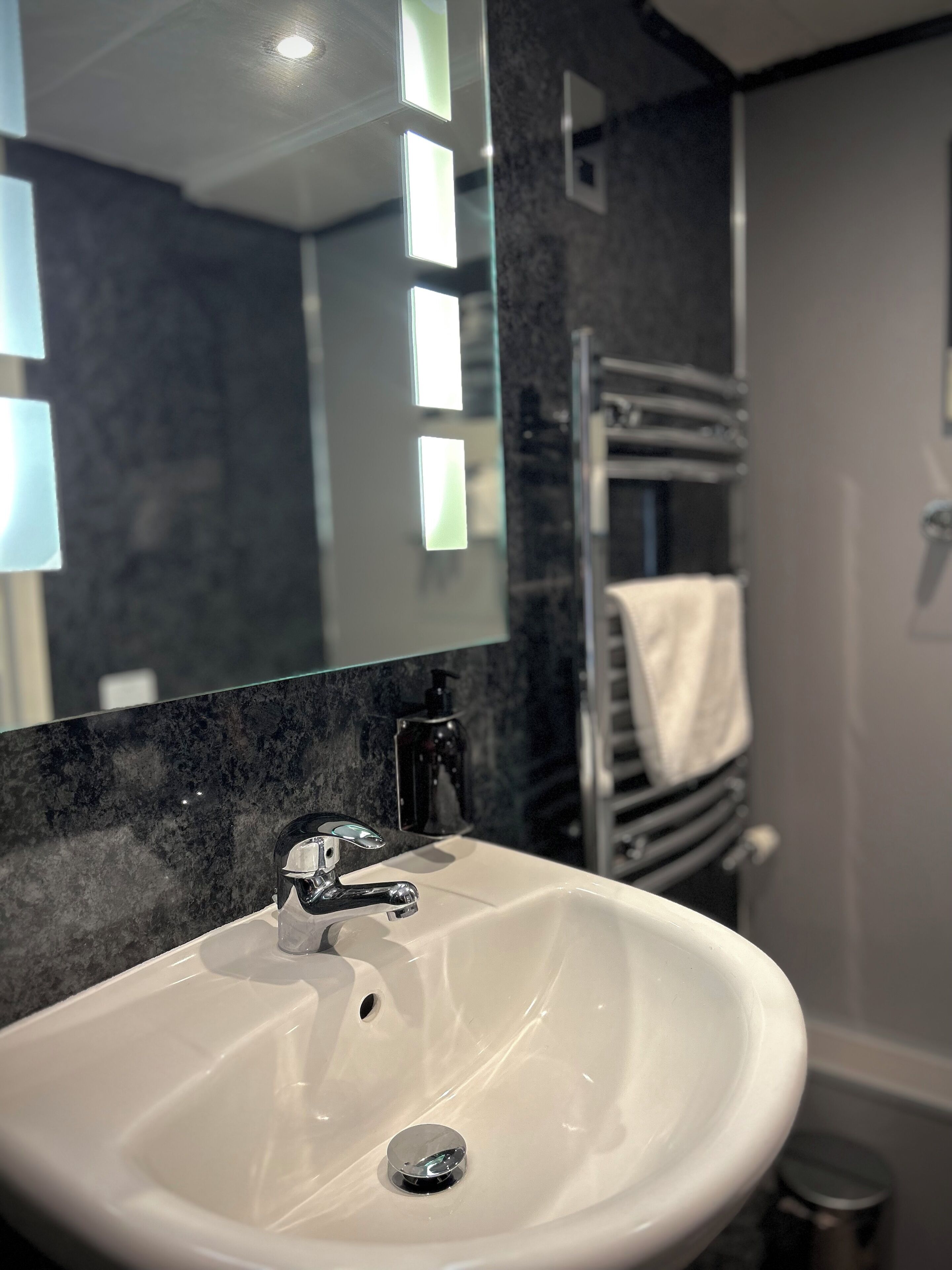 A bathroom with a white sink, a mirror, and a towel rack.