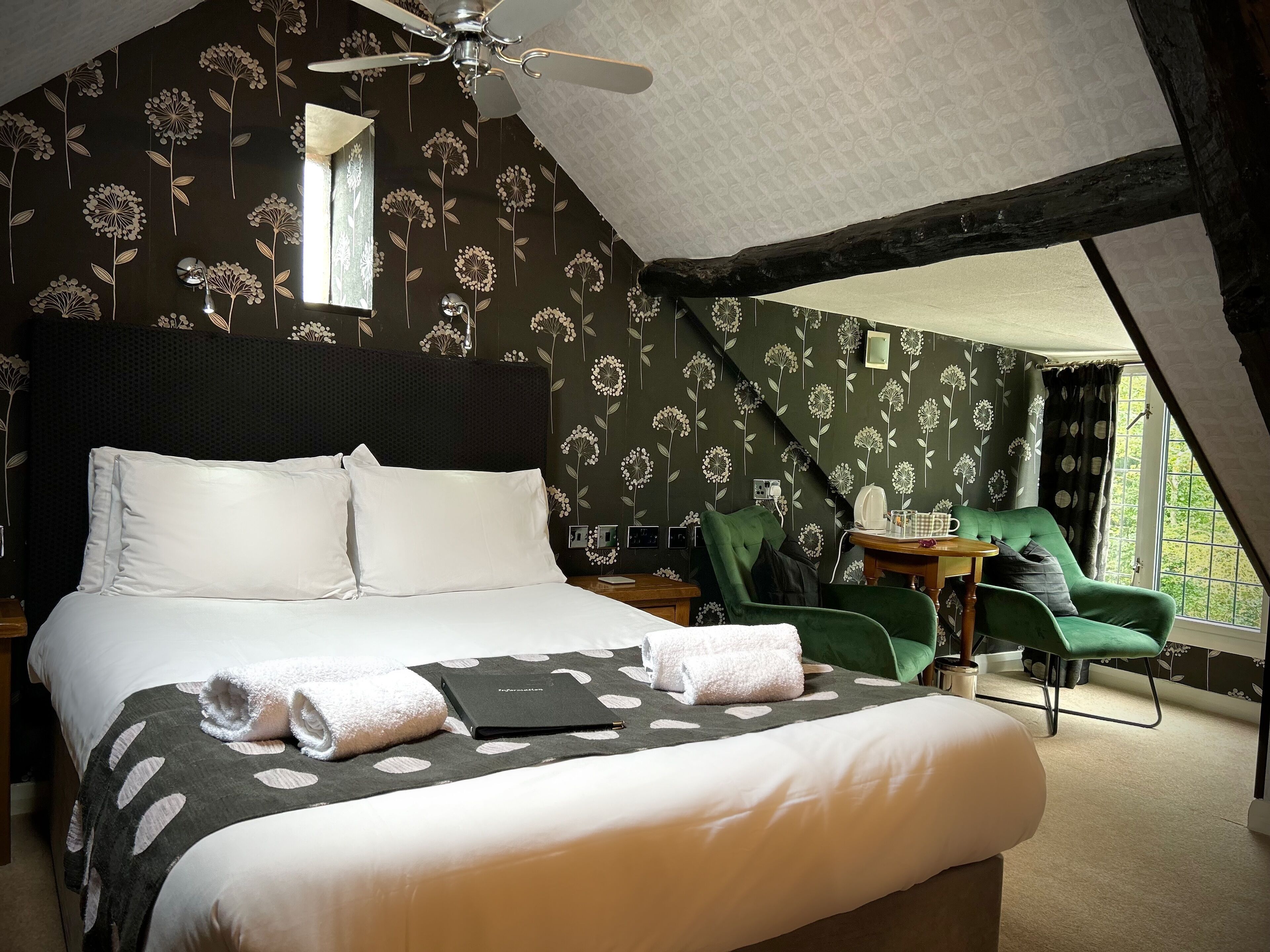 A bedroom with a large bed, a ceiling fan, and a window with curtains.